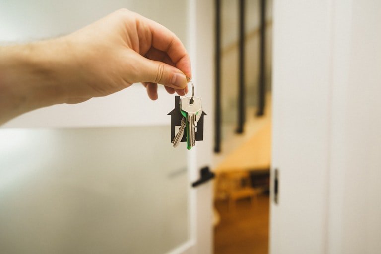 Hand holding new house keys at an open front door