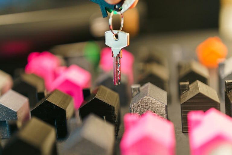 House key held above a row of miniature homes